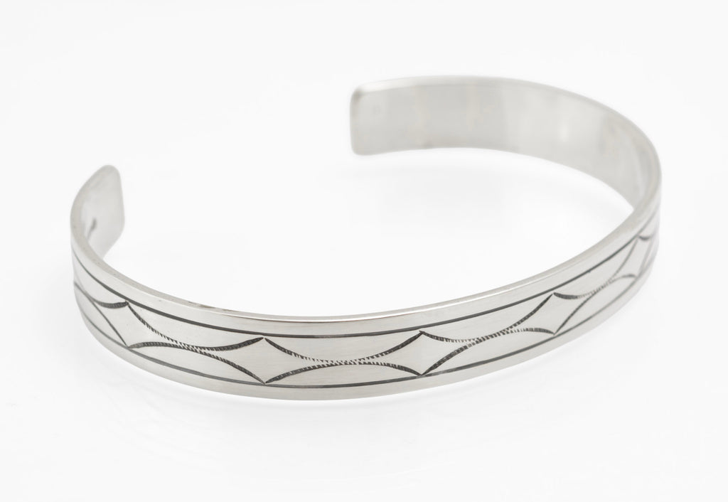 Vintage sterling silver open cuff bangle three quarter view showing hand engraved geometric star pattern with fine hatched ground and parallel border lines on white background