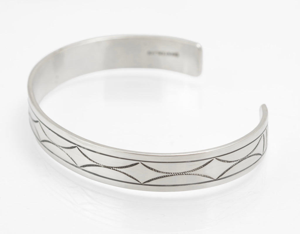 Inside of vintage sterling silver cuff bangle showing pictorial maker's mark and STERLING stamp on white background
