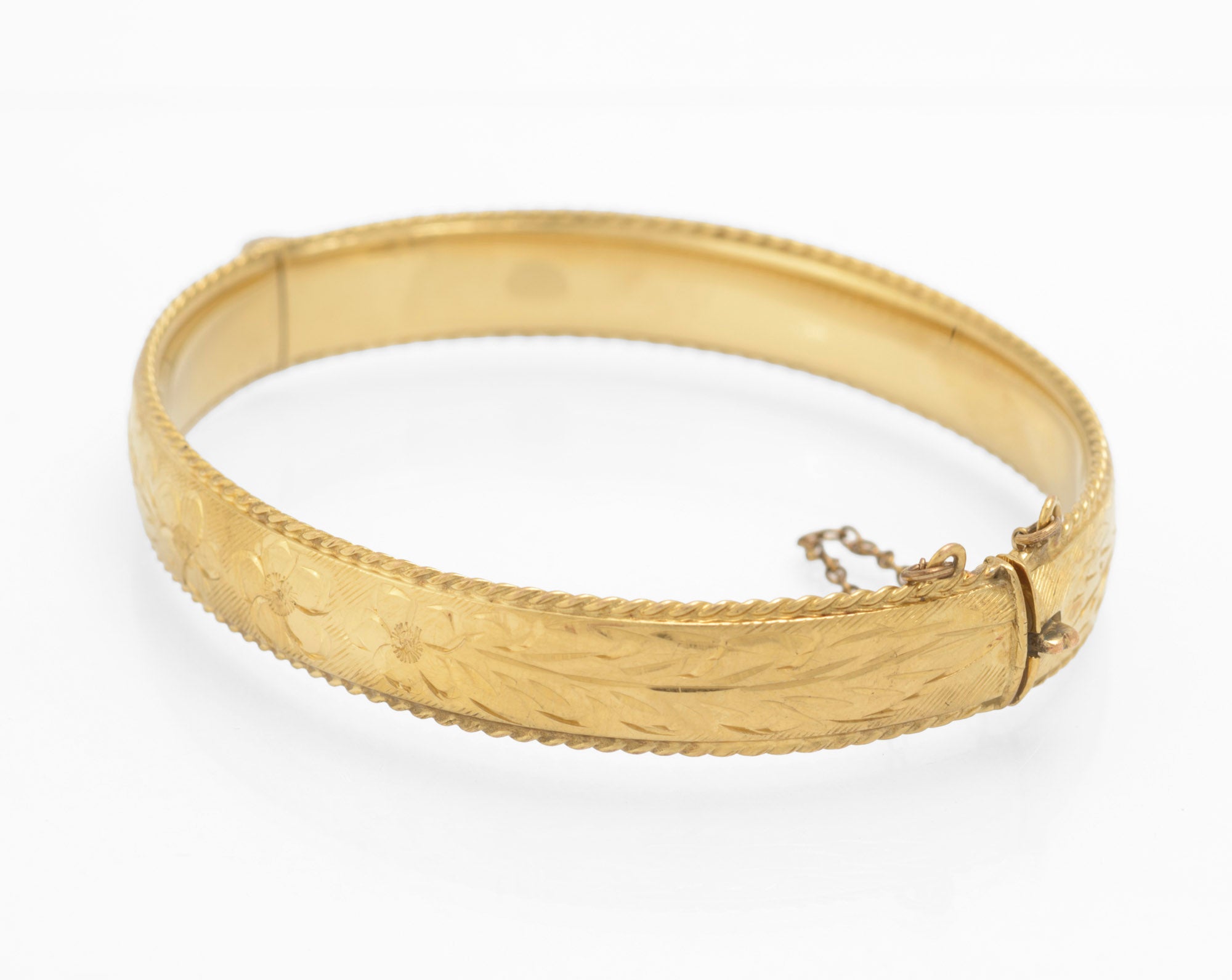 Vintage 1/5 9ct rolled gold hinged bangle showing hand engraved open daisy flowers and scrolling stems across front face with rope twist border on white background