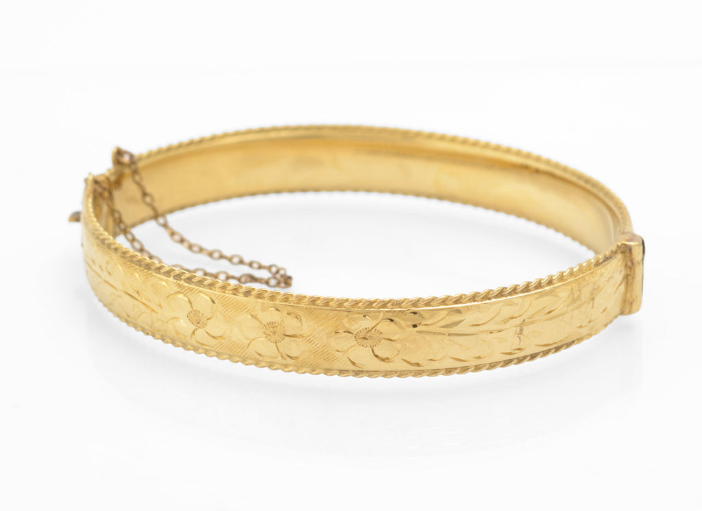Vintage 1/5 9ct rolled gold hinged bangle side view showing rope twist border edge and engraved floral decoration with safety chain on white background