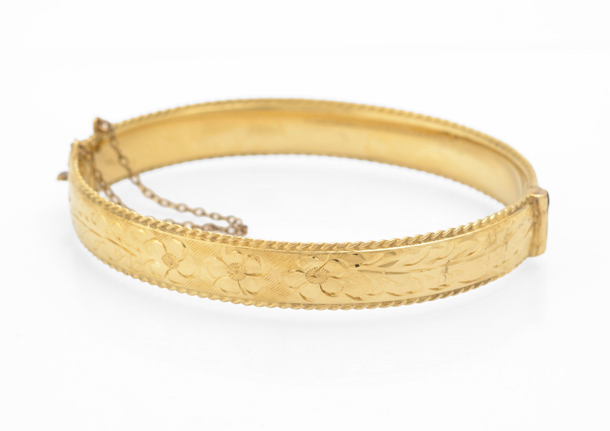 Vintage 1/5 9ct rolled gold hinged bangle open showing slide clasp mechanism and safety chain attachment with rope twist border detail on white background