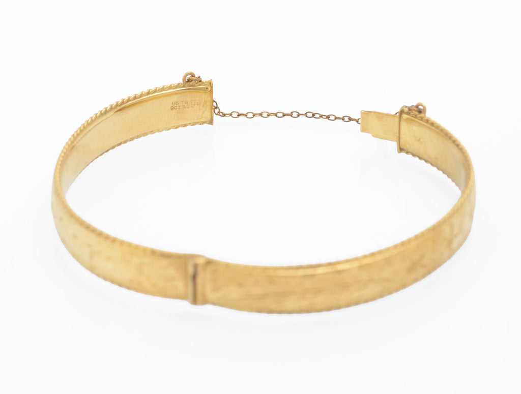 Inside of vintage 1/5 9ct rolled gold hinged bangle clasp section showing 1/5TH 9CT RG stamp and JS within shield maker's mark of Joseph Smith and Sons Birmingham on white background