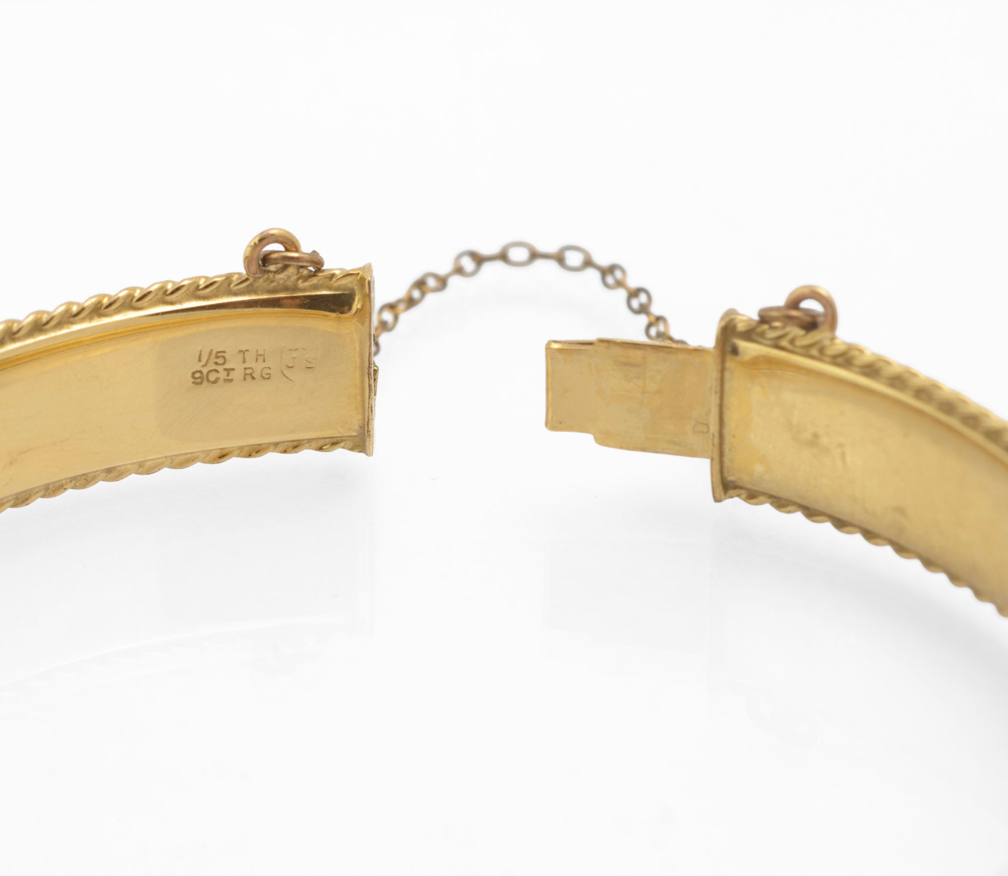 Close up of vintage 1/5 9ct rolled gold hinged bangle open clasp showing slide clasp mechanism safety chain and 1/5TH 9CT RG mark with JS shield maker's mark on white background