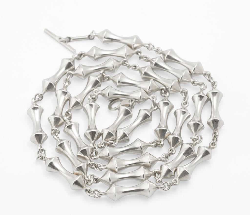 Vintage sterling silver long necklace coiled on white background showing full volume of 44g sterling silver double cone reel link chain with T-bar toggle visible at top