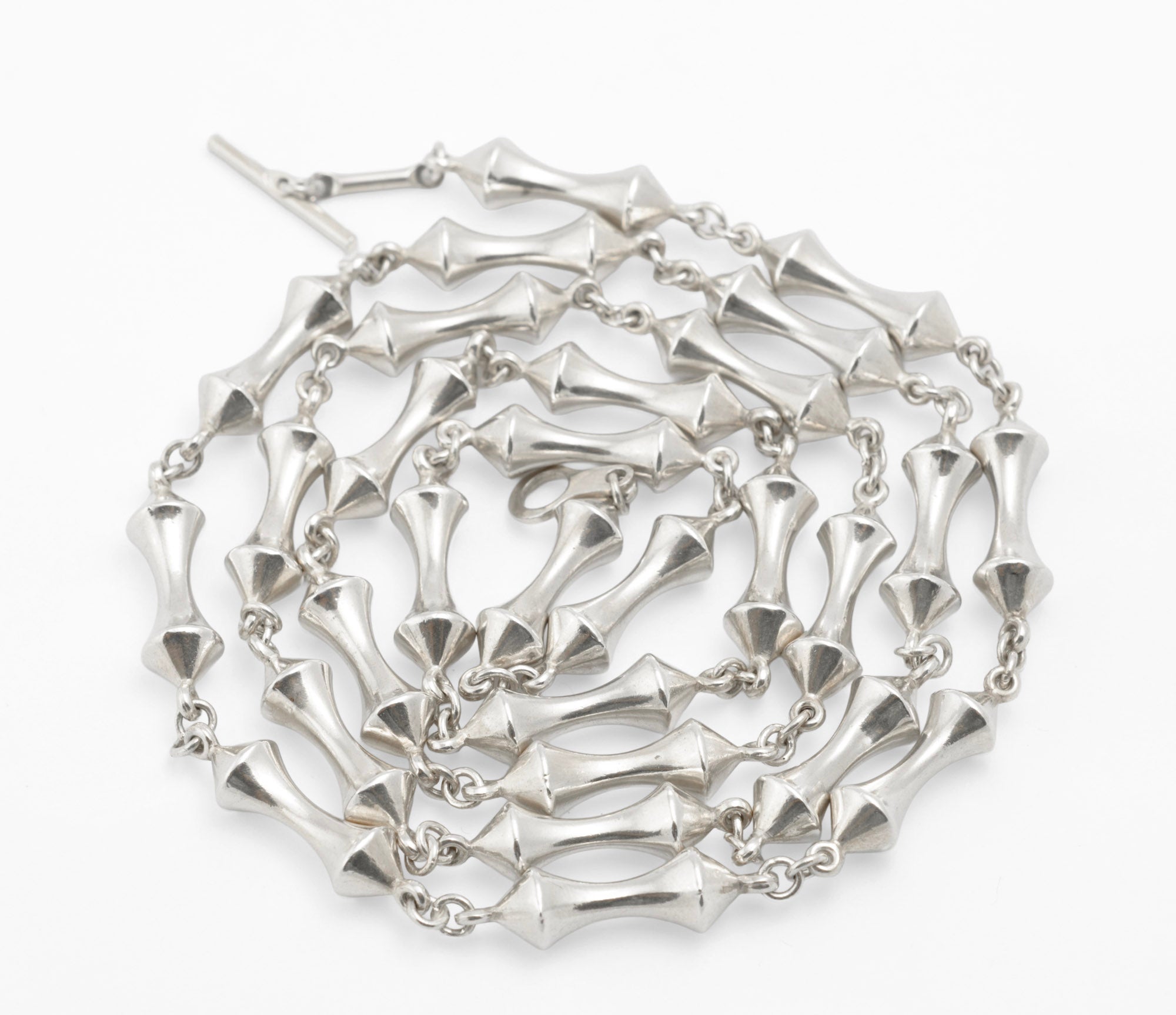 Vintage sterling silver long necklace coiled on white background showing full volume of 44g sterling silver double cone reel link chain with T-bar toggle visible at top