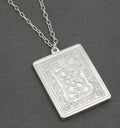 Vintage sterling silver St Valentine's Day ingot pendant by John Pinches 1977 showing Celtic interlaced knotwork with heart shapes on stippled ground within acanthus scrolling border on grey background with silver chain