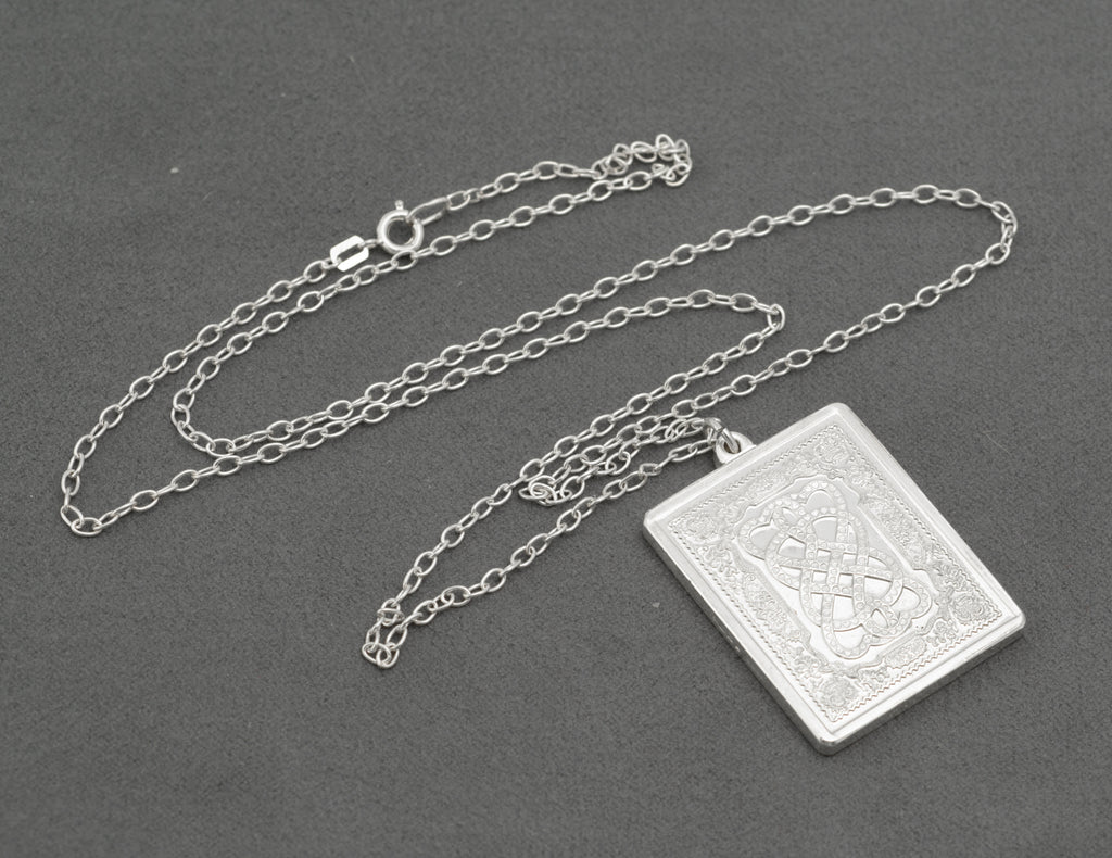 Full length view of vintage sterling silver John Pinches 1977 St Valentine's Day Celtic knotwork pendant on 61cm silver cable chain with spring ring clasp on grey background