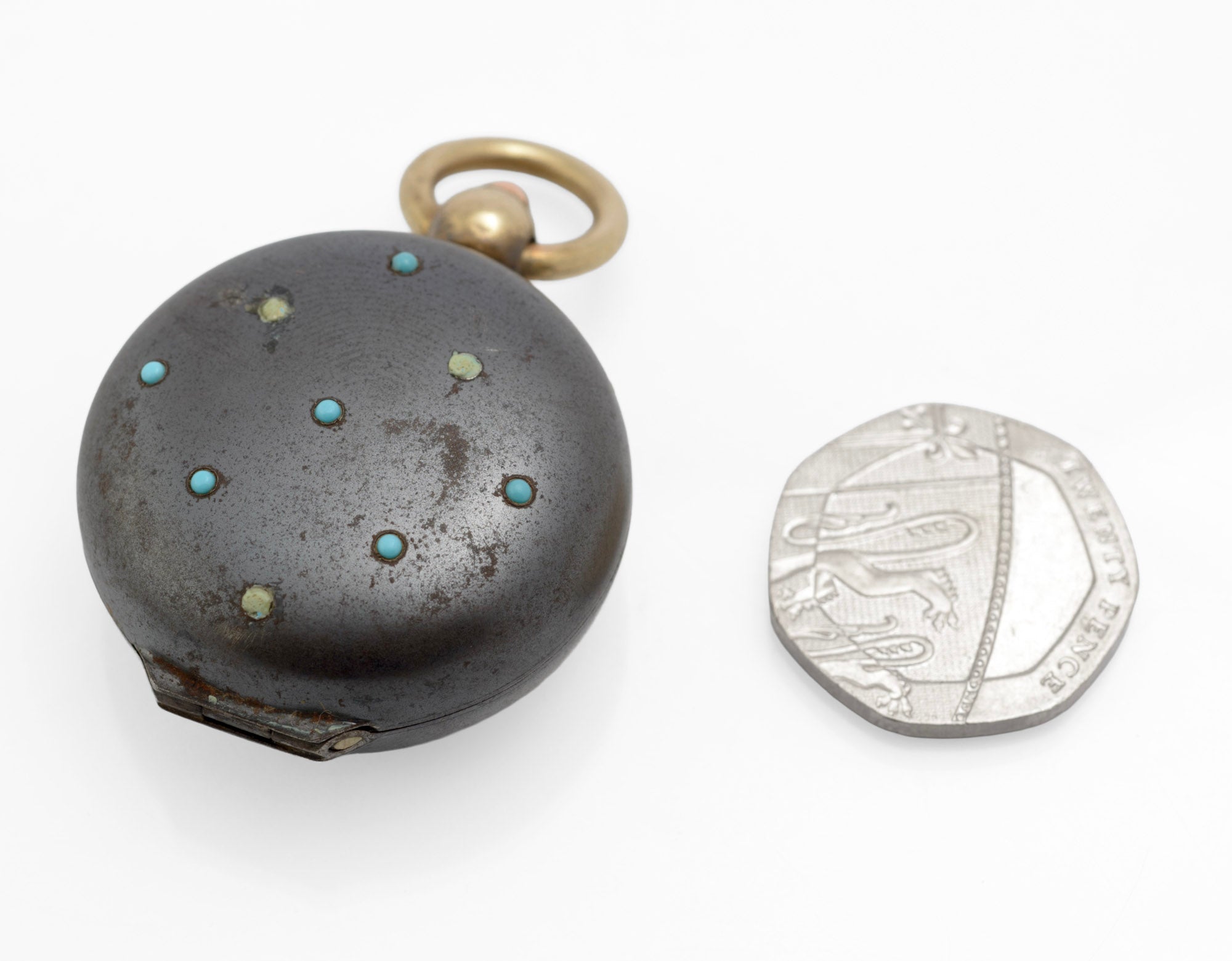 Antique gun metal sovereign case with turquoise decoration front view next to 20p coin for scale showing scattered cabochon arrangement on white background