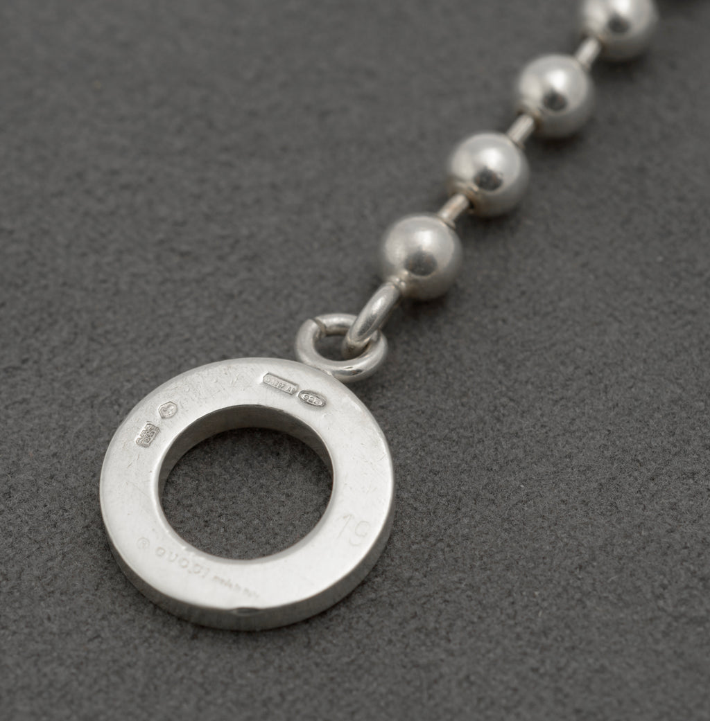 Reverse of Gucci sterling silver bracelet toggle ring showing Gucci Made in Italy copyright mark Italian hallmark 925 silver mark International Convention mark and maker registration 1697 AR on dark grey background