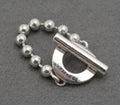 Gucci sterling silver Boule Toggle ring close up of front face showing circular toggle section with fixed polished silver T-bar and GUCCI branding in recessed lettering with ball chain band on dark grey background