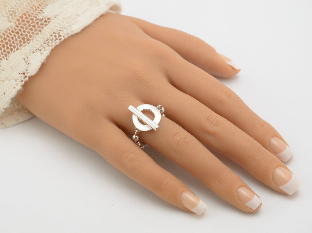 Gucci sterling silver Boule Toggle ring worn on mannequin hand showing circular toggle section and T-bar at front with flexible ball chain band draping around finger on white background