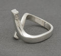 Gucci sterling silver crossover ring showing deeply punched GUCCI lettering on inner surface of upper diagonal bar with twisted band construction on grey background