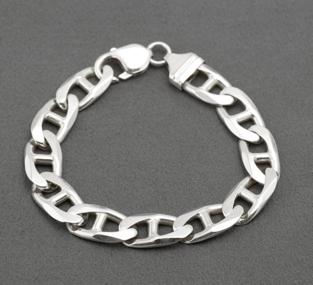 Vintage sterling silver broad mariner link bracelet laid in circle on dark grey background showing flat oval links with central dividing bars and lobster clasp with shaped ribbed terminal
