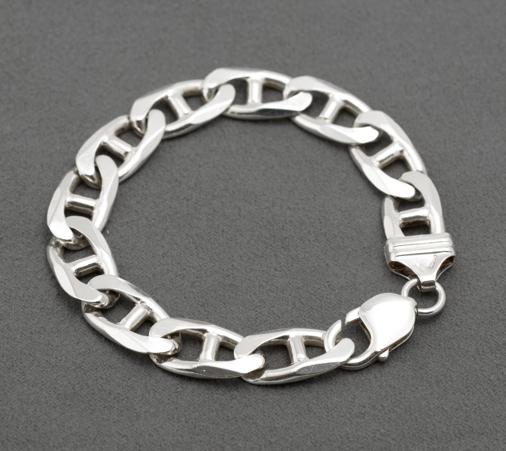 Vintage sterling silver mariner link bracelet laid in circle on dark grey background showing alternating link orientation and lobster clasp with connecting ring to shaped terminal
