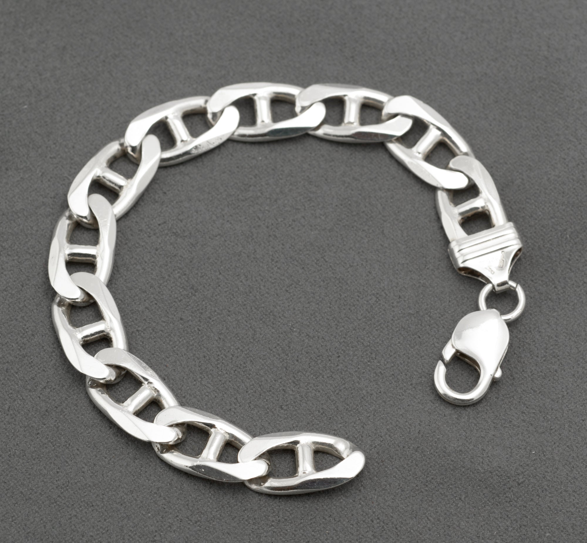 Vintage sterling silver broad mariner link bracelet laid open on light grey background showing full 19.5cm length flat oval links with central bars and lobster clasp unclasped