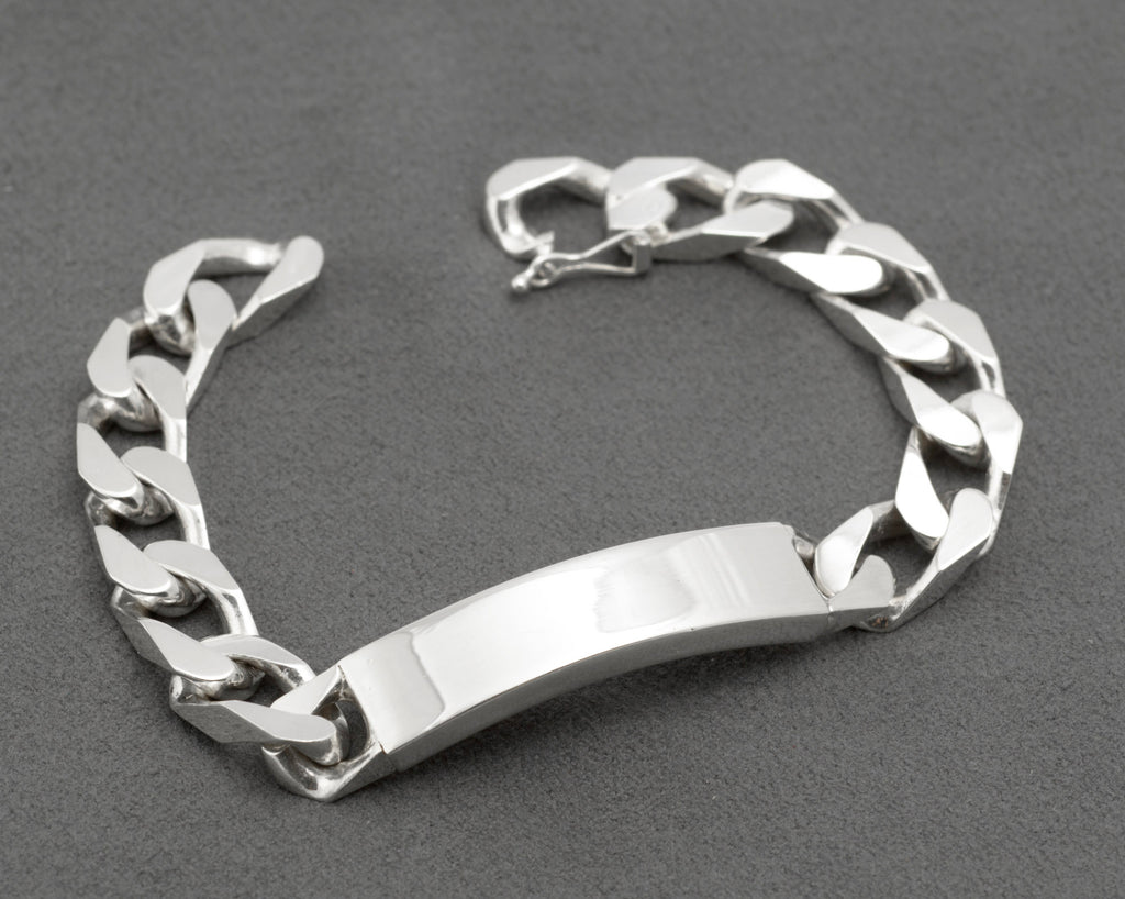 Italian sterling silver ID bracelet on dark grey cone bracelet stand showing plain mirror polished curved ID panel and broad flattened curb link chain with push-piece clasp on white background