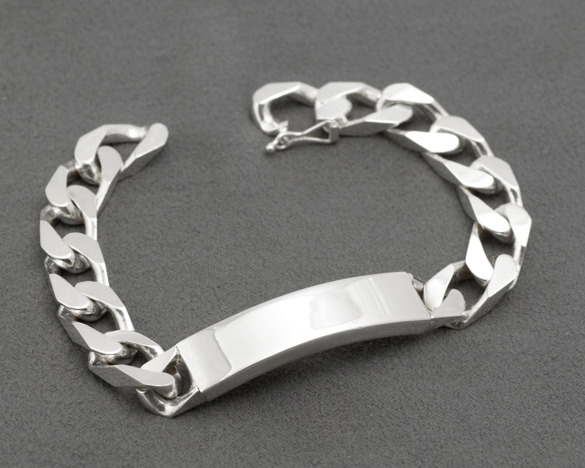 Italian sterling silver ID bracelet on dark grey cone bracelet stand showing plain mirror polished curved ID panel and broad flattened curb link chain with push-piece clasp on white background