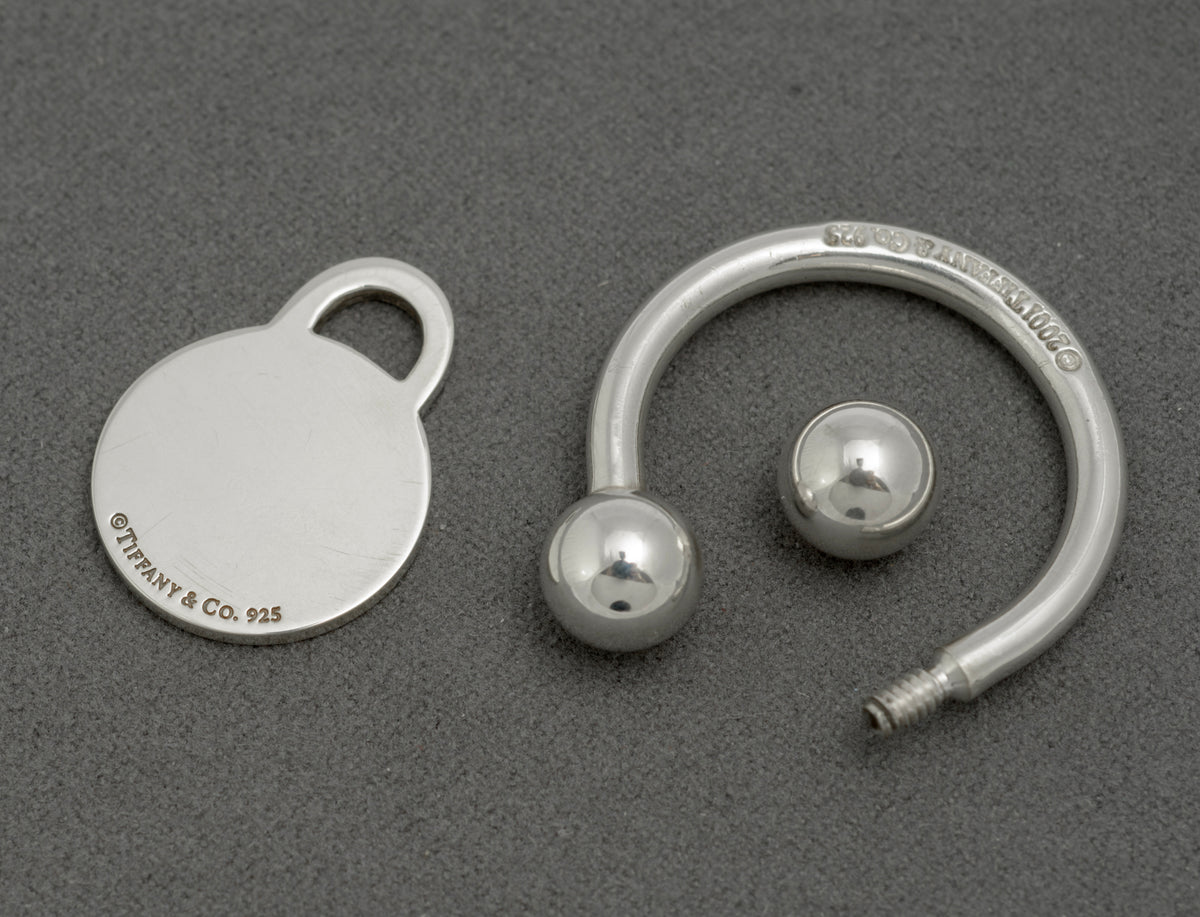 Tiffany and Co sterling silver Return to Tiffany screwball key ring disassembled showing front of tag engraved Please Return to Tiffany and Co New York A30319 and ring with 925 mark