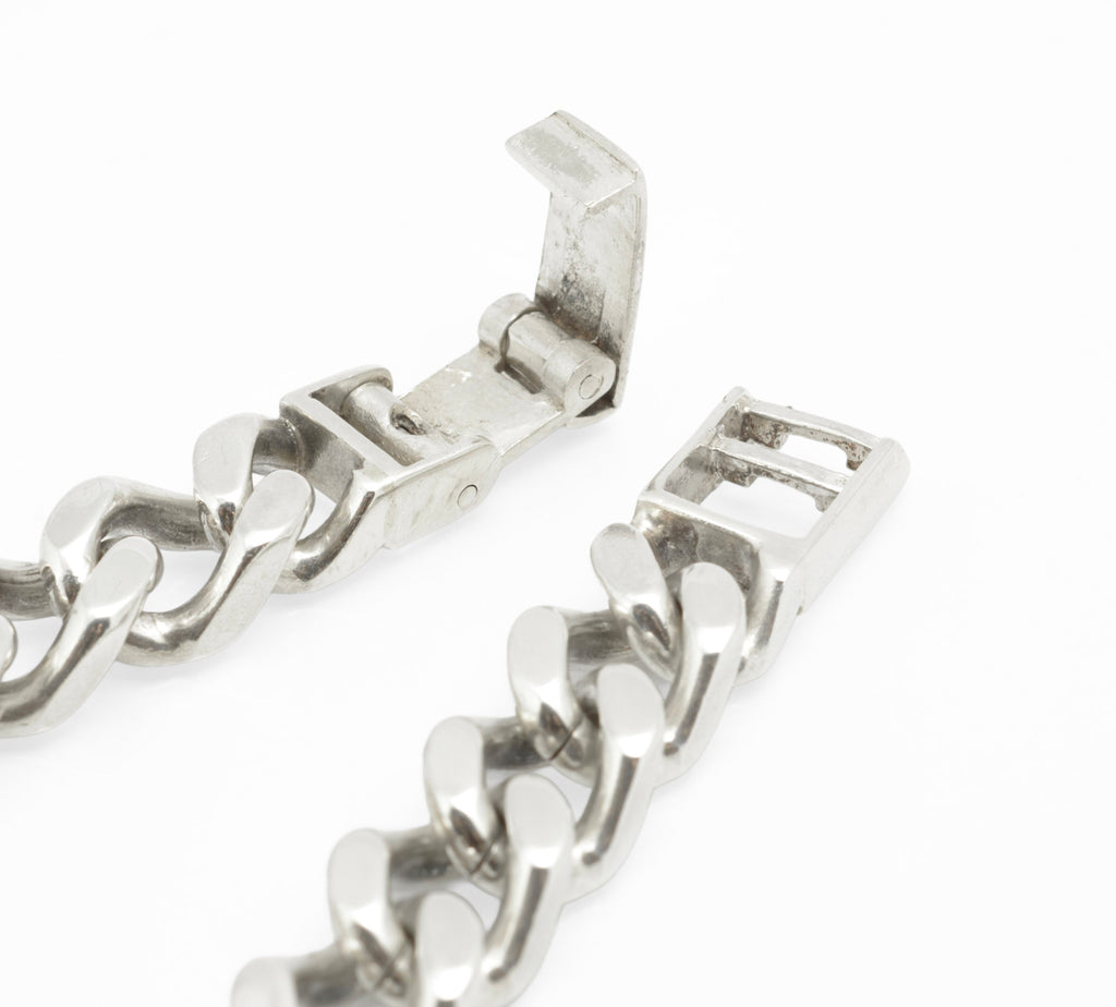 Vintage sterling silver ID bracelet angled view on grey background showing depth and scale of broad curb links and thick ID panel
