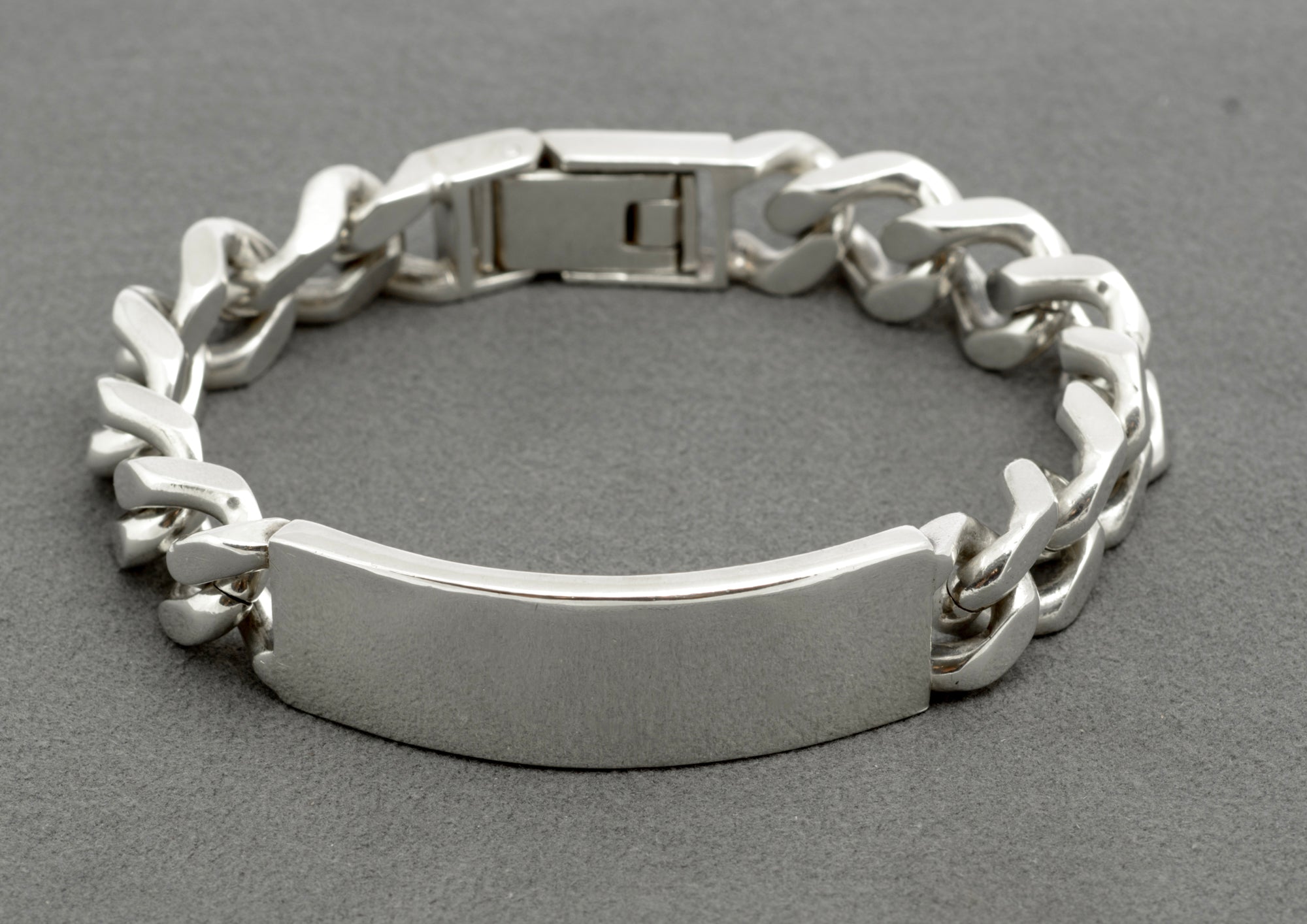 Vintage sterling silver ID bracelet top down view on grey background showing full length, plain ID panel and folding box clasp