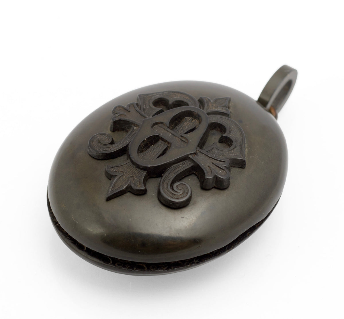 Antique Victorian vulcanite mourning locket side profile view showing domed body, brass hinge and vulcanite suspension loop with brass connecting ring