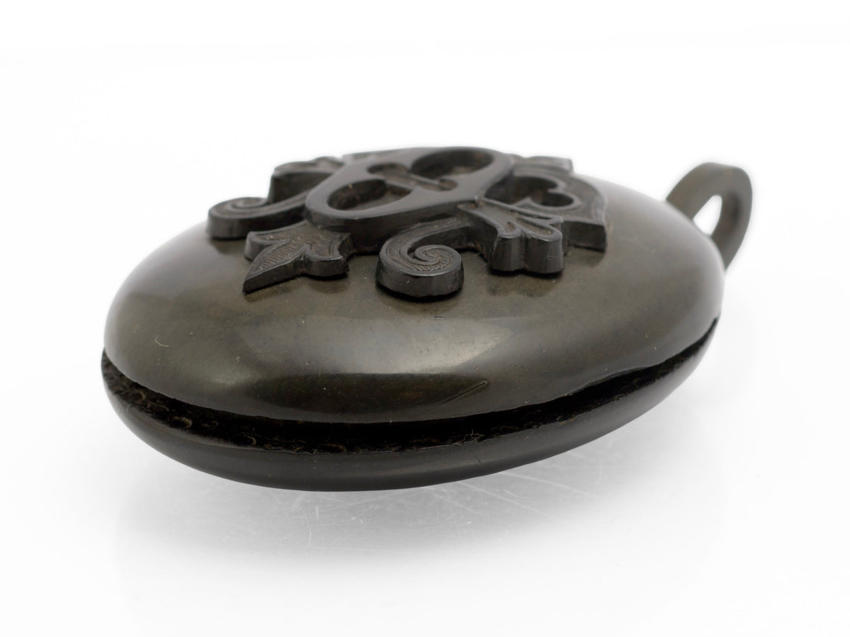 Antique Victorian vulcanite mourning locket front view showing raised cross bottony fleury panel with scrolling foliate surround