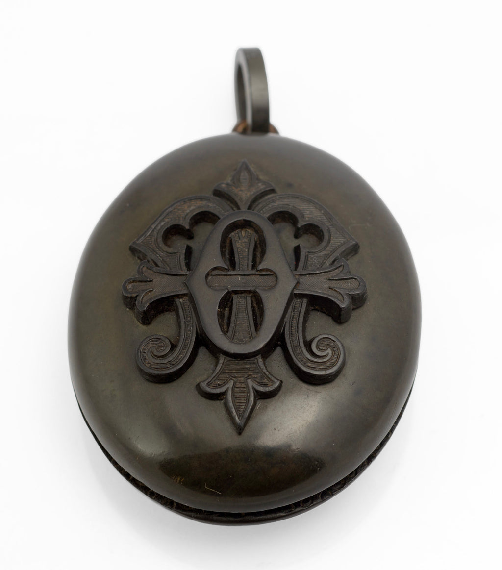 Antique Victorian vulcanite mourning locket open close up showing glazed compartment with domed glass and finely engraved interior decoration