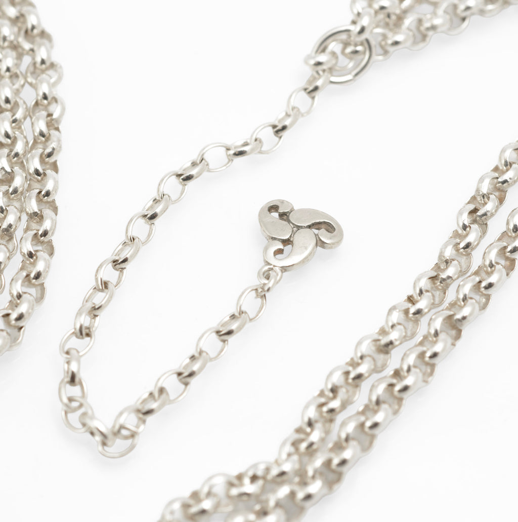Vintage Ola Gorie sterling silver necklet close up of openwork triskelion centre section showing scrolling forms and hallmark on white background