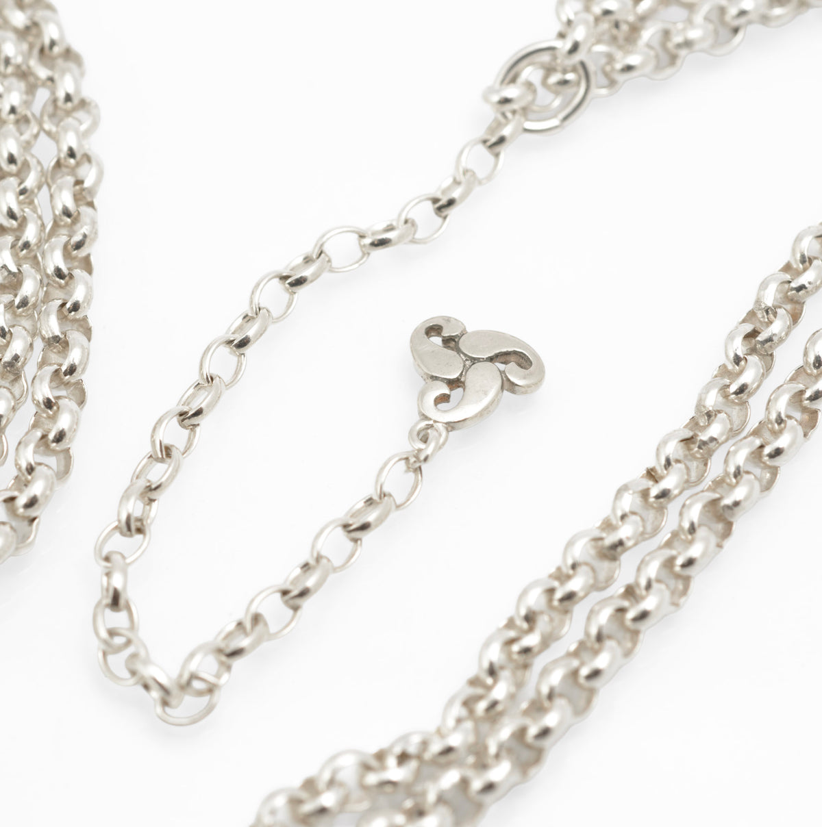 Vintage Ola Gorie sterling silver necklet close up of openwork triskelion centre section showing scrolling forms and hallmark on white background