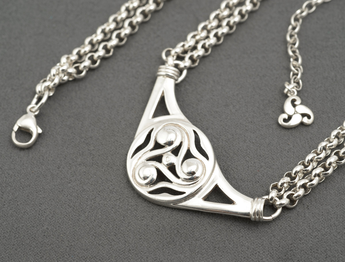 Vintage Ola Gorie sterling silver necklet close up of triskelion centre on grey background showing polished scroll forms and openwork detail