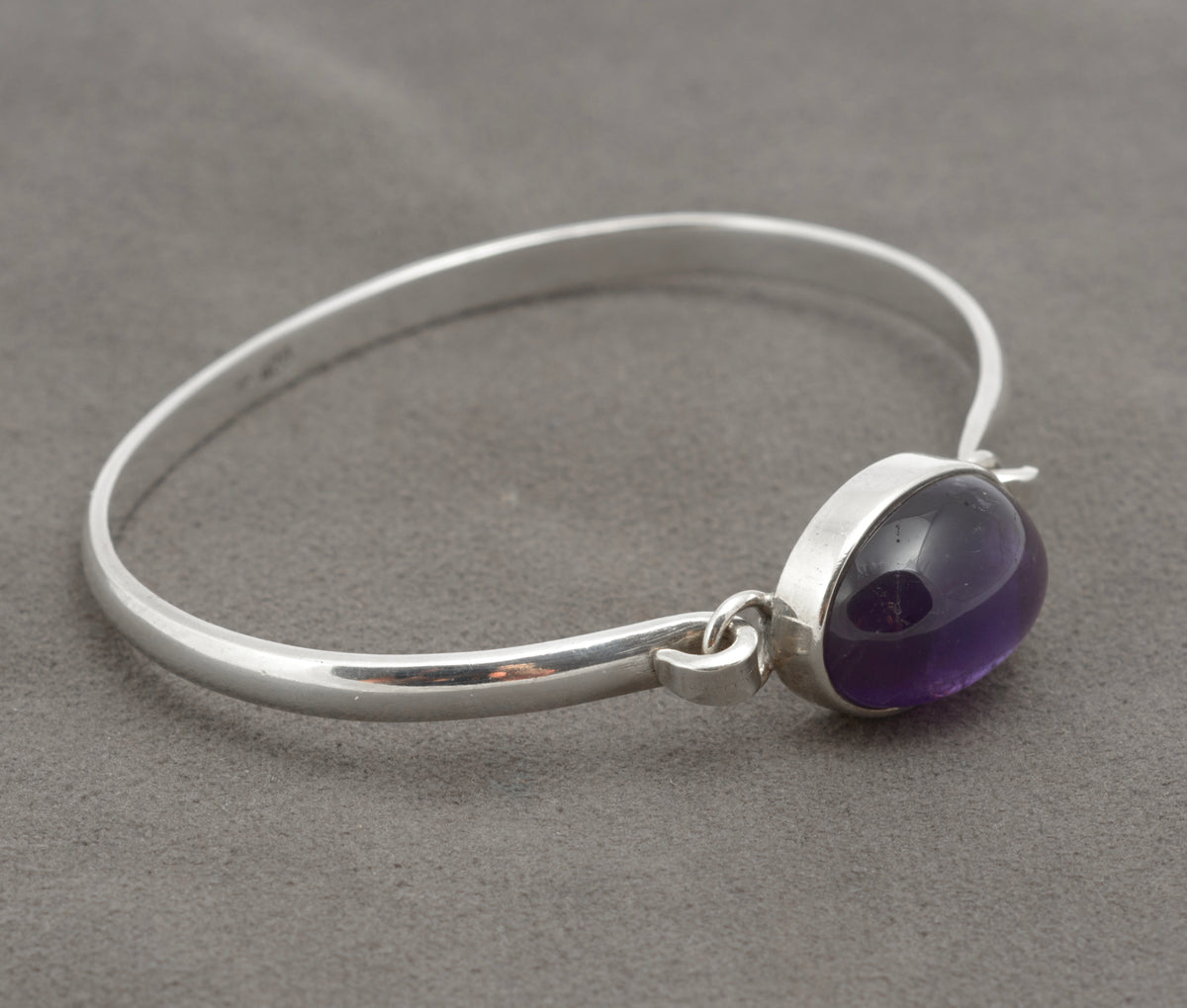 Vintage sterling silver amethyst cabochon bangle, close view of oval stone, bezel and silver band