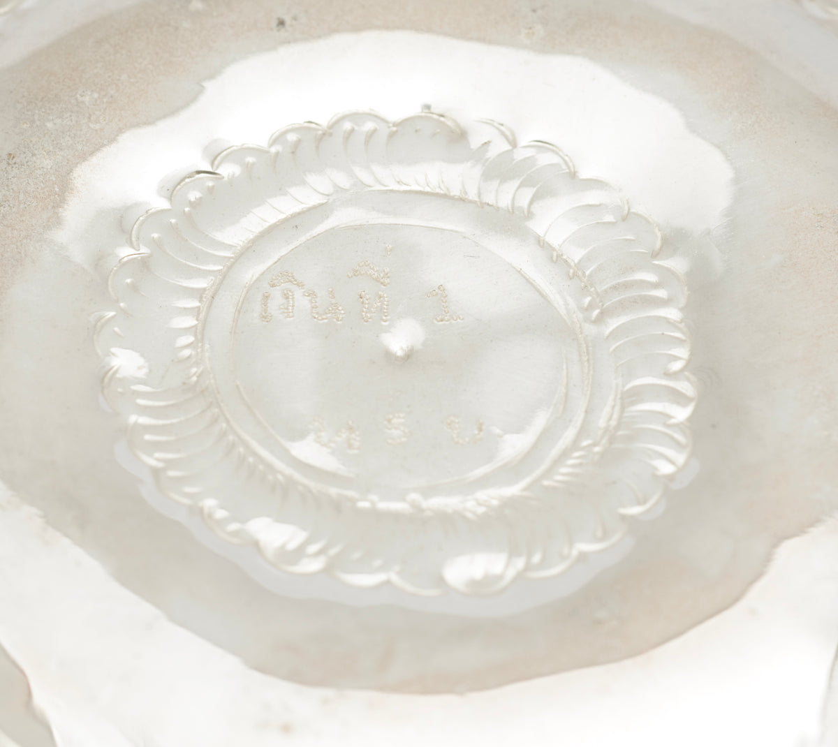 Thai silver offering bowl from a front angle showing the scalloped lower edge and repousse decoration