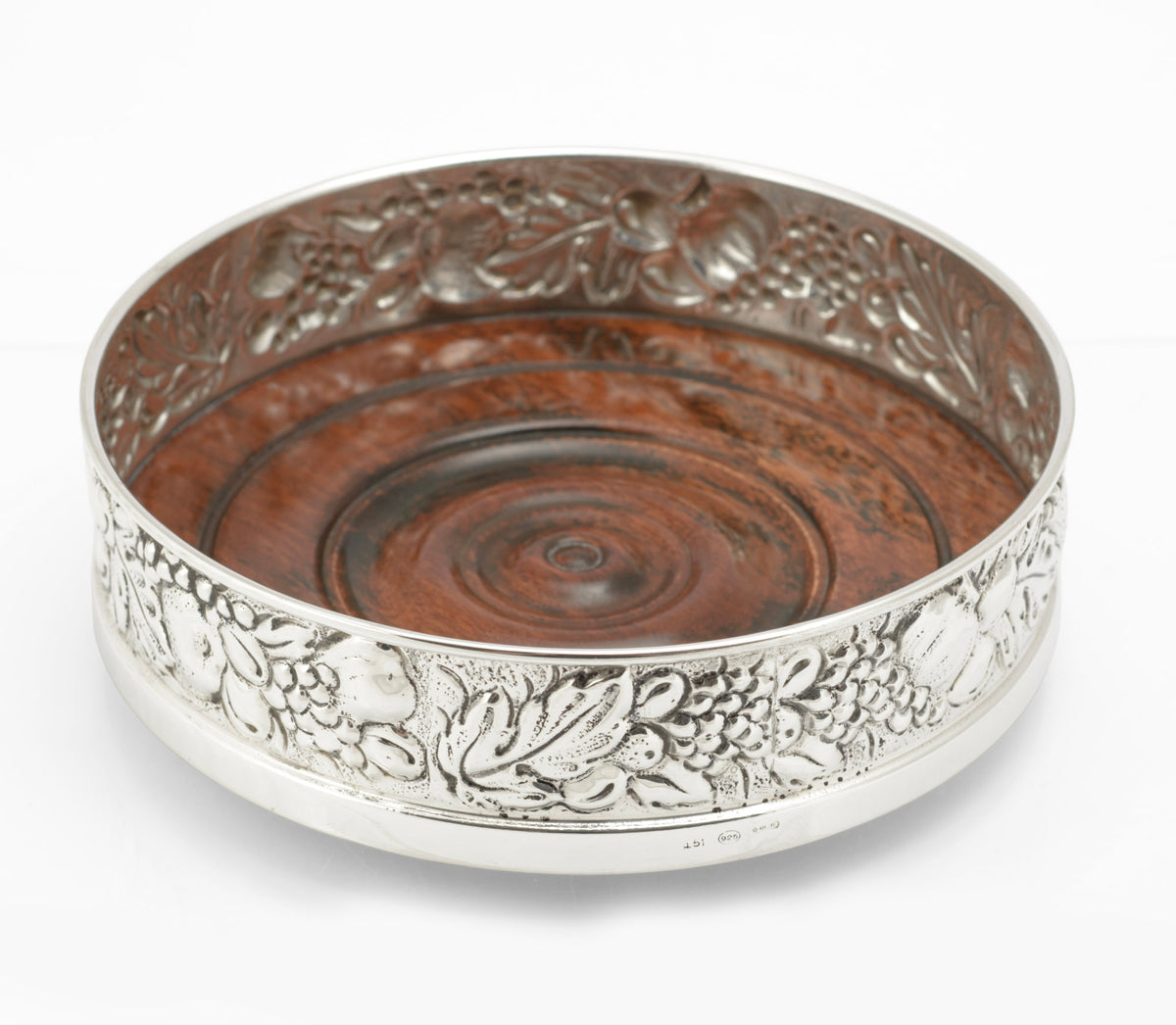 Sterling silver repousse bottle coaster by Falsini Ferruccio Florence, grapevine decoration, turned hardwood base - three quarter view