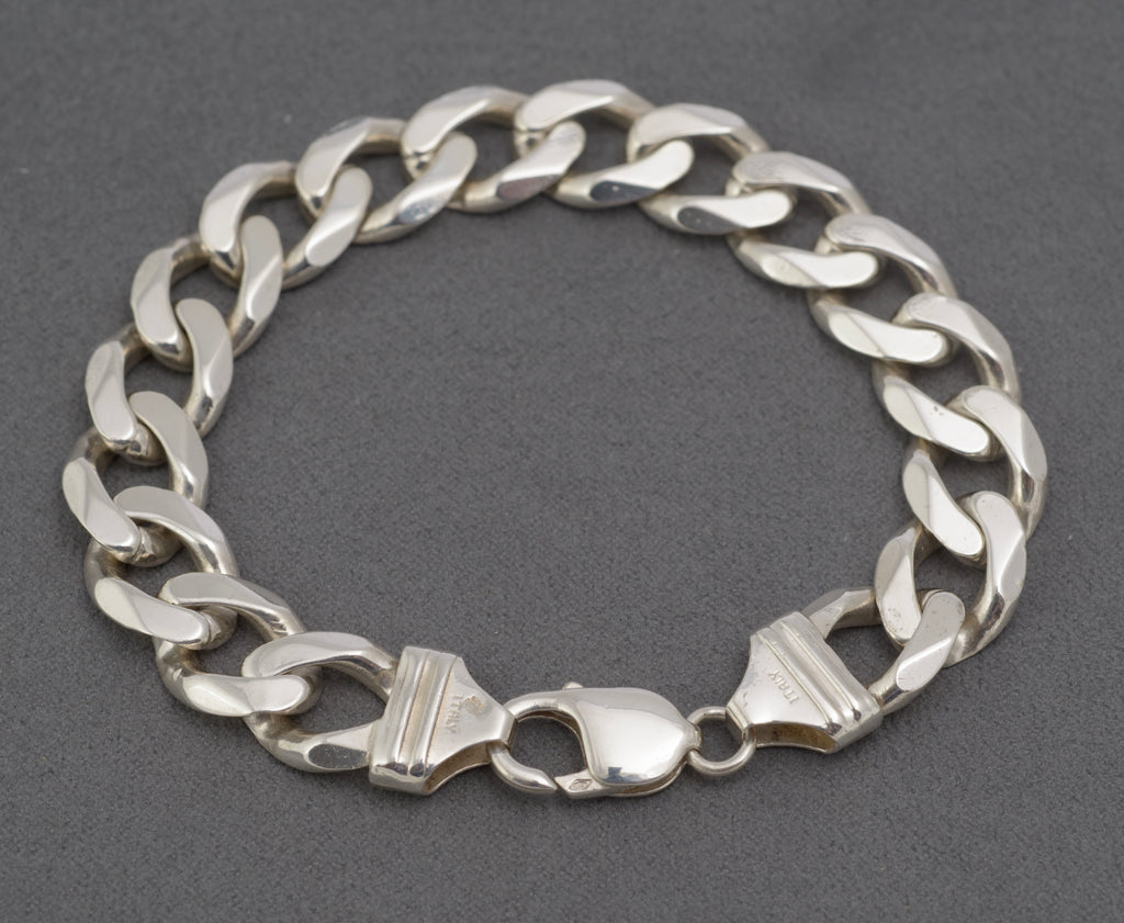 Italian sterling silver flat curb link bracelet laid out with lobster clasp open
