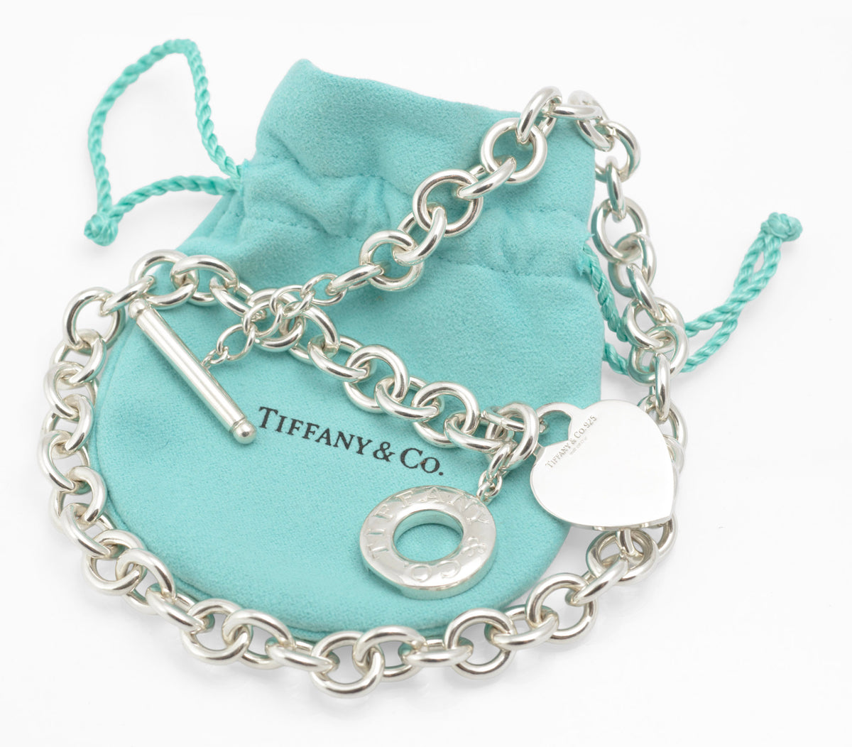Angled view of vintage Tiffany and Co sterling silver Heart Tag necklace displayed with its soft pouch