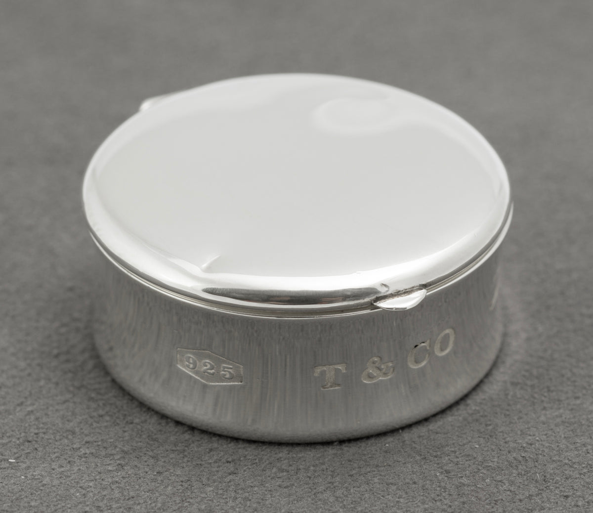 Closed front view of vintage Tiffany & Co sterling silver 1837 circular pill box with concave profile