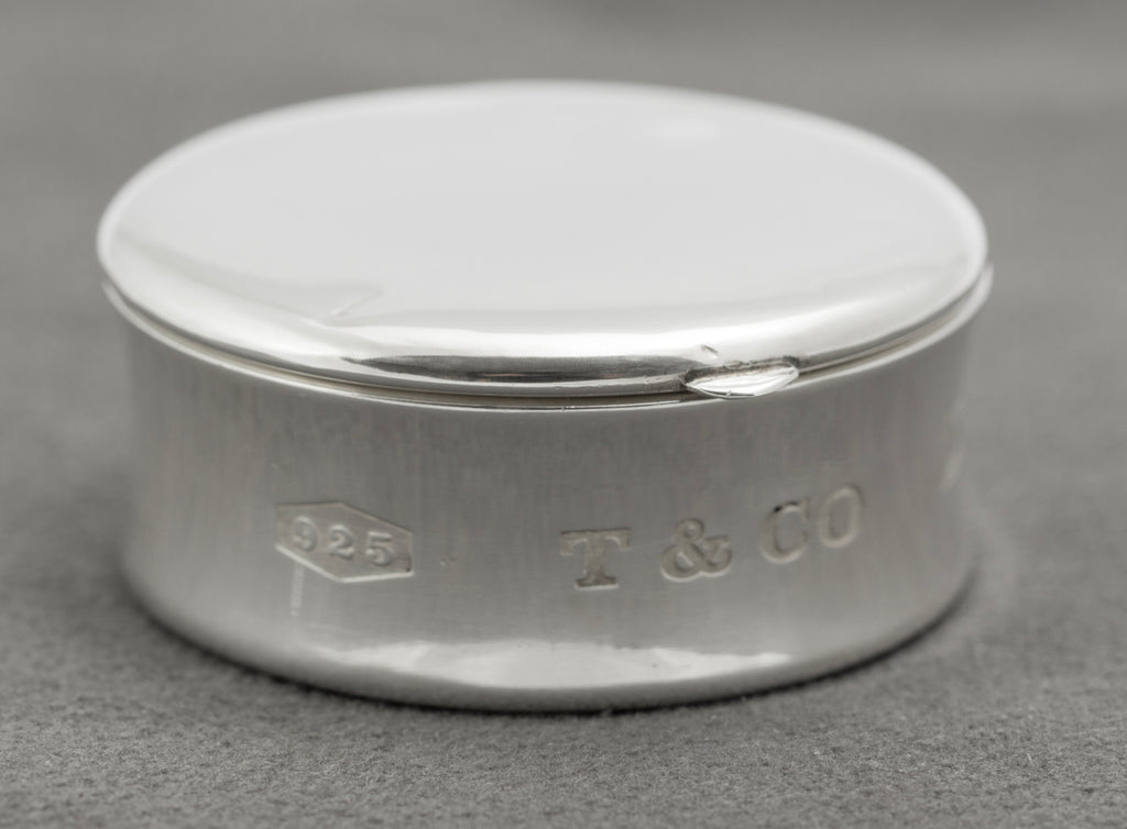 Closed side view showing the curved silver wall and hinged lid of Tiffany & Co 1837 pill box