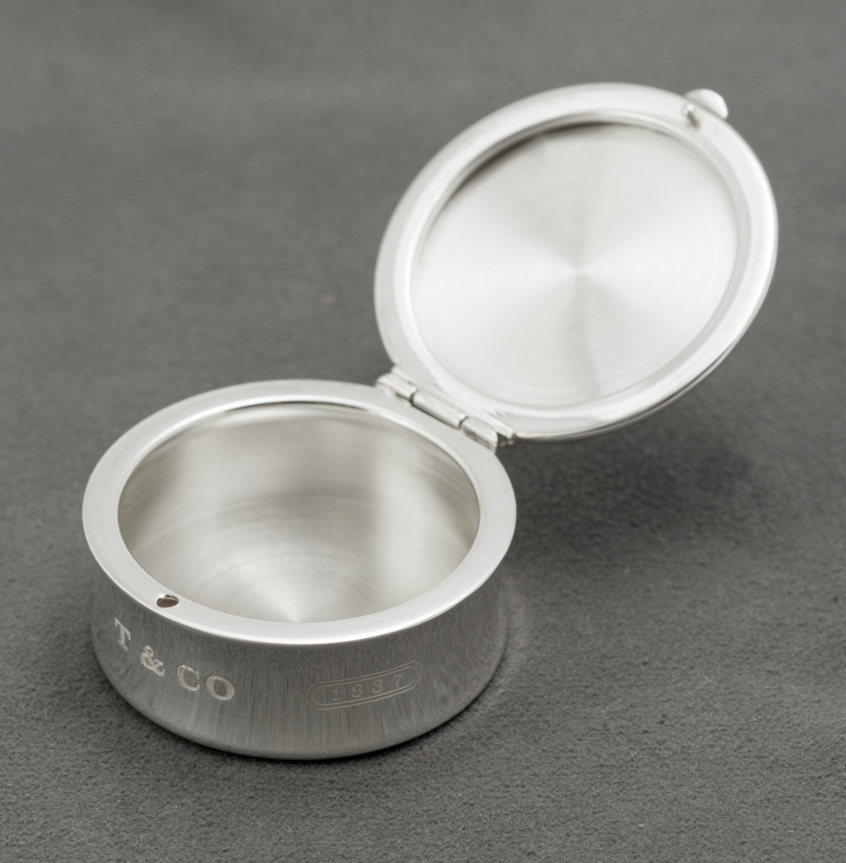 Open vintage Tiffany & Co sterling silver 1837 pill box showing its plain silver interior