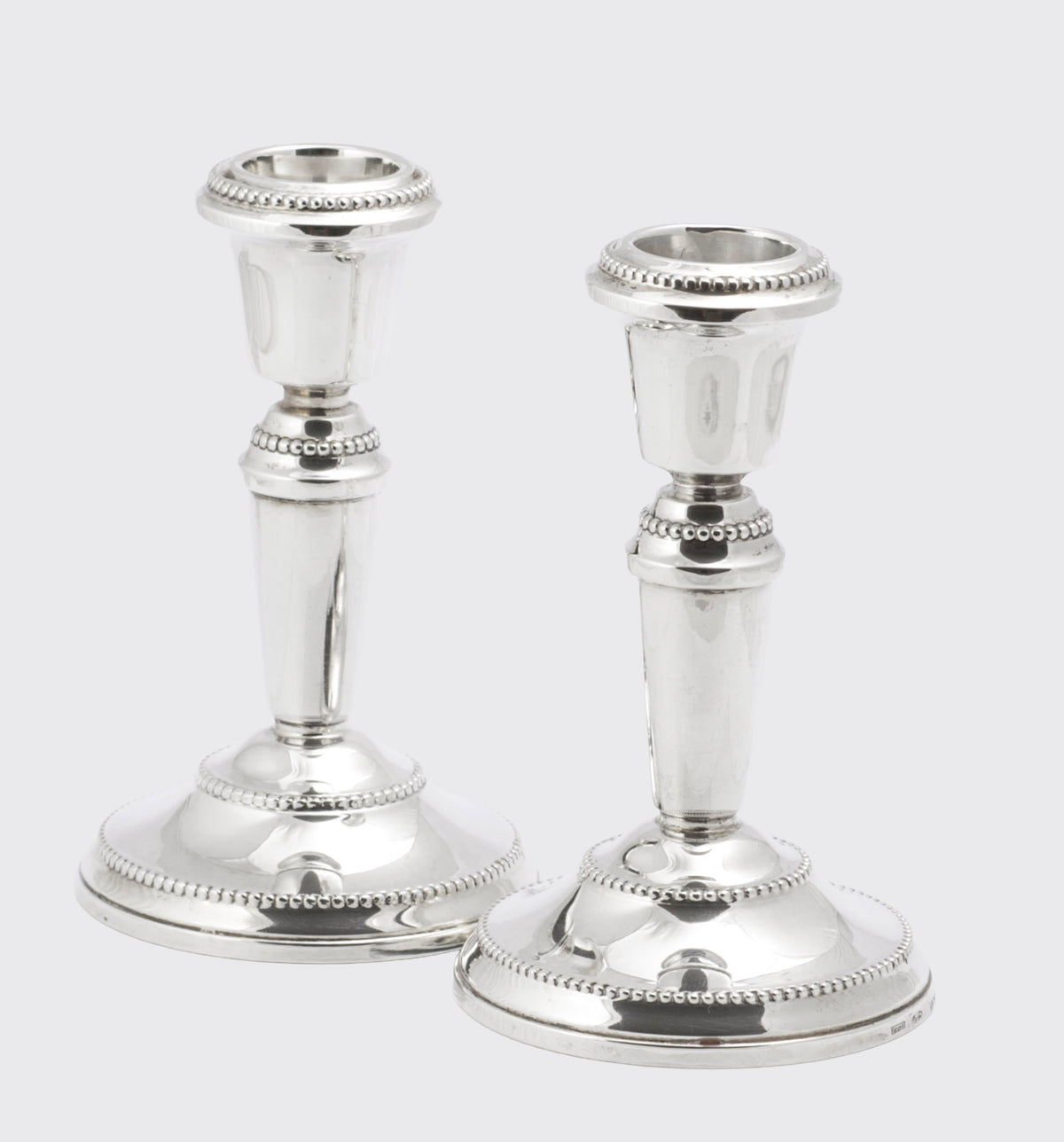 Pair of sterling silver candlesticks showing the green felt underside of one weighted base
