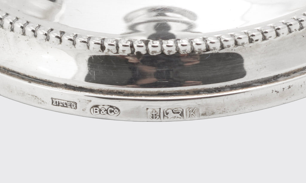 Angled view of a pair of vintage sterling silver candlesticks with traditional beaded detailing