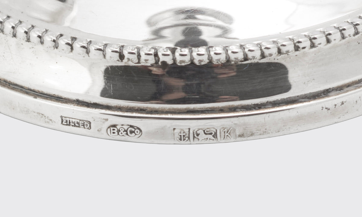 Angled view of a pair of vintage sterling silver candlesticks with traditional beaded detailing