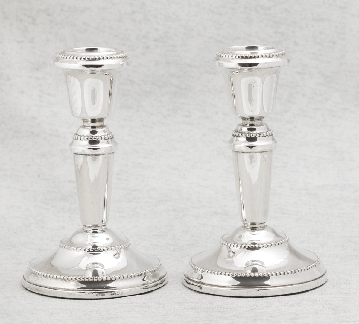 Matching pair of vintage sterling silver candlesticks with broad circular bases and classical form