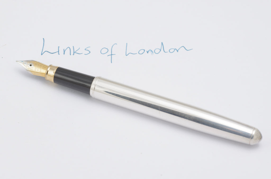 Uncapped Links of London silver plated fountain pen showing the black grip and gold tone nib