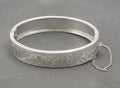 Vintage sterling silver bangle by N. C. Reading & Co, showing the engraved floral front and attached safety chain