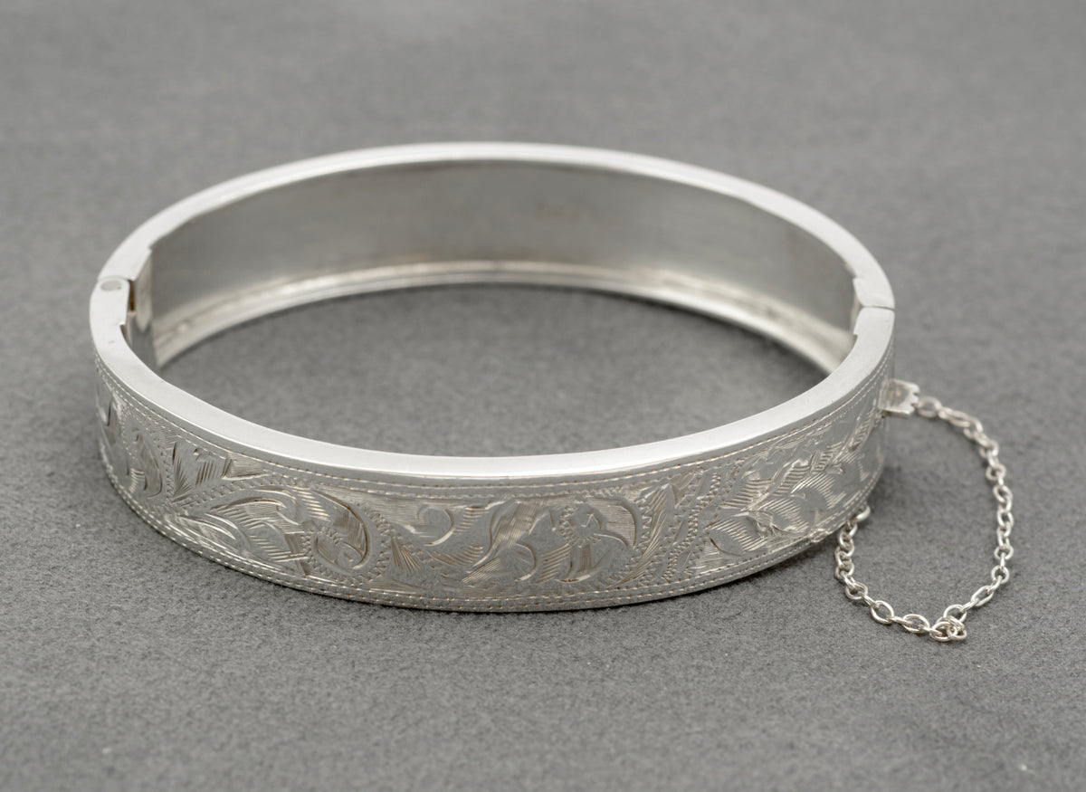Vintage sterling silver bangle by N. C. Reading & Co, showing the engraved floral front and attached safety chain
