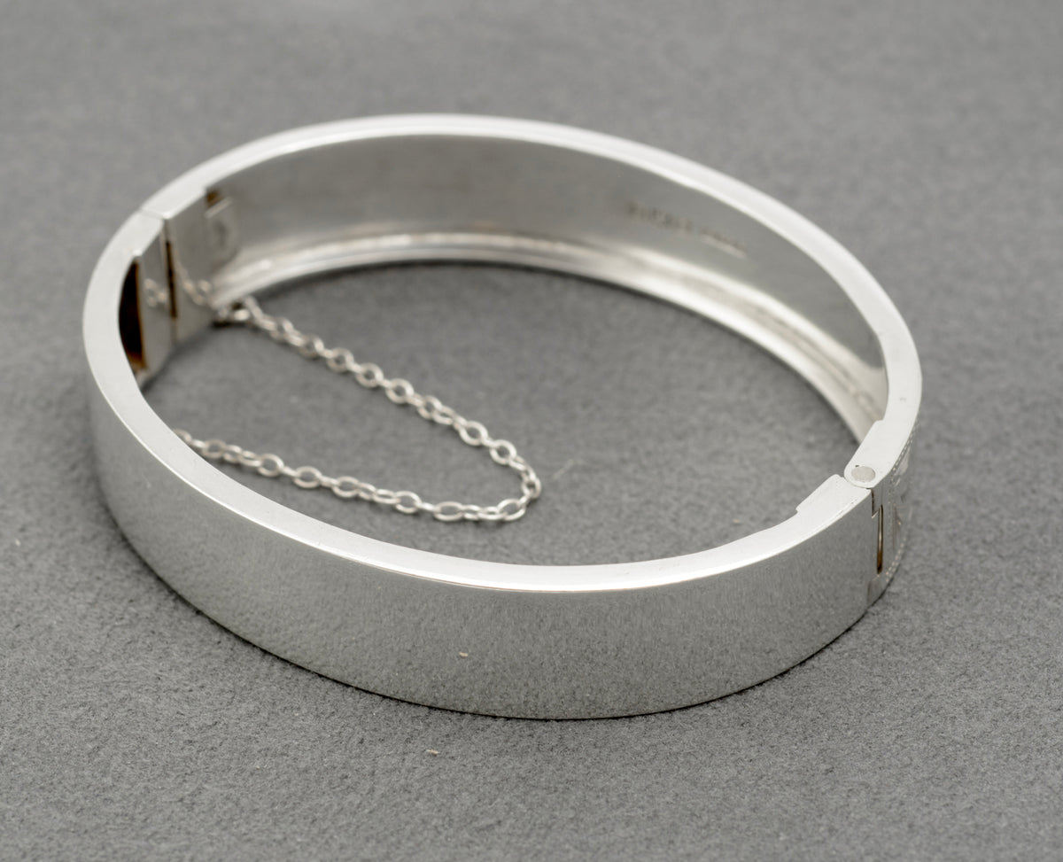 Angled view of the engraved floral and foliate decoration on the sterling silver bangle
