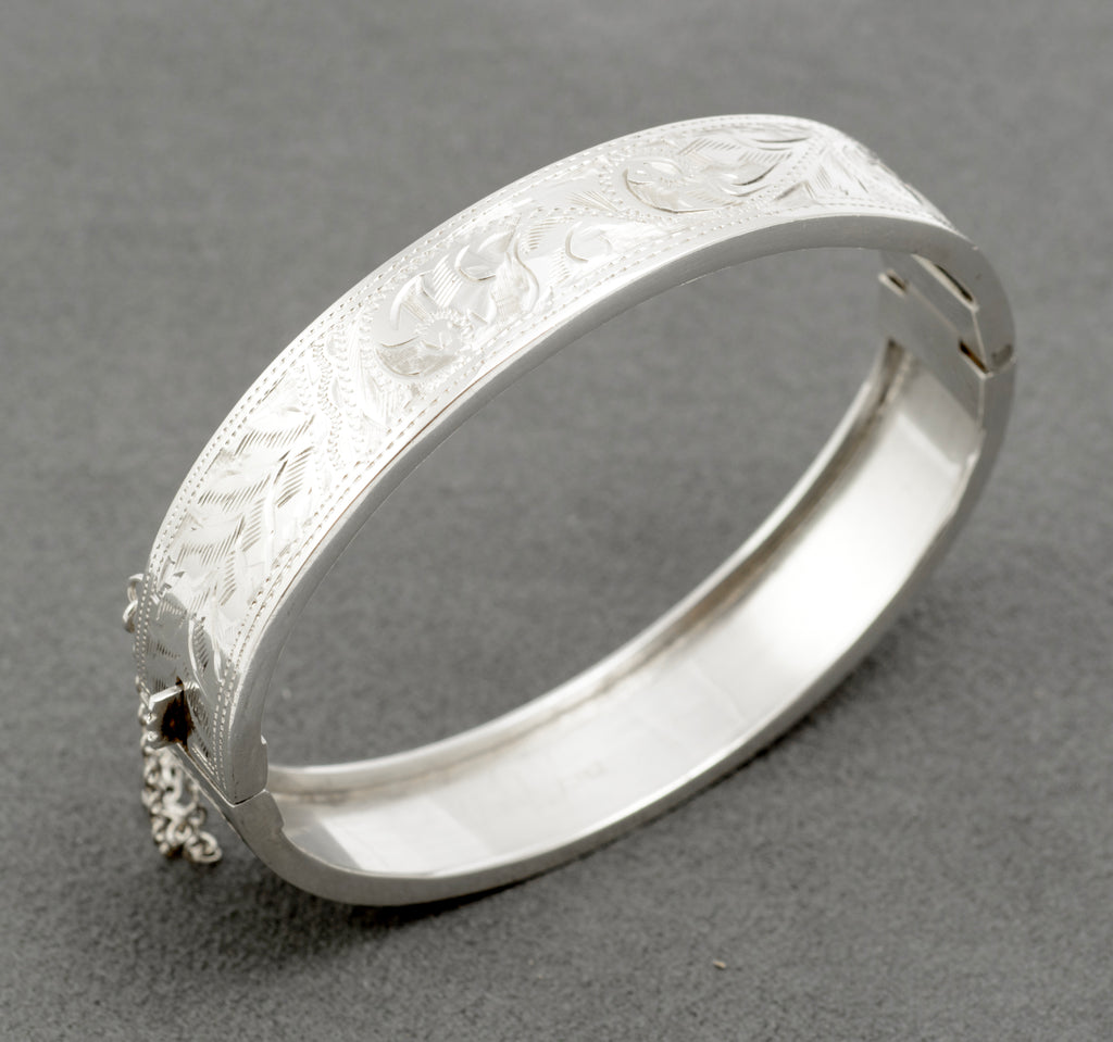 Three quarter view of the engraved sterling silver hinged bangle and its fastening