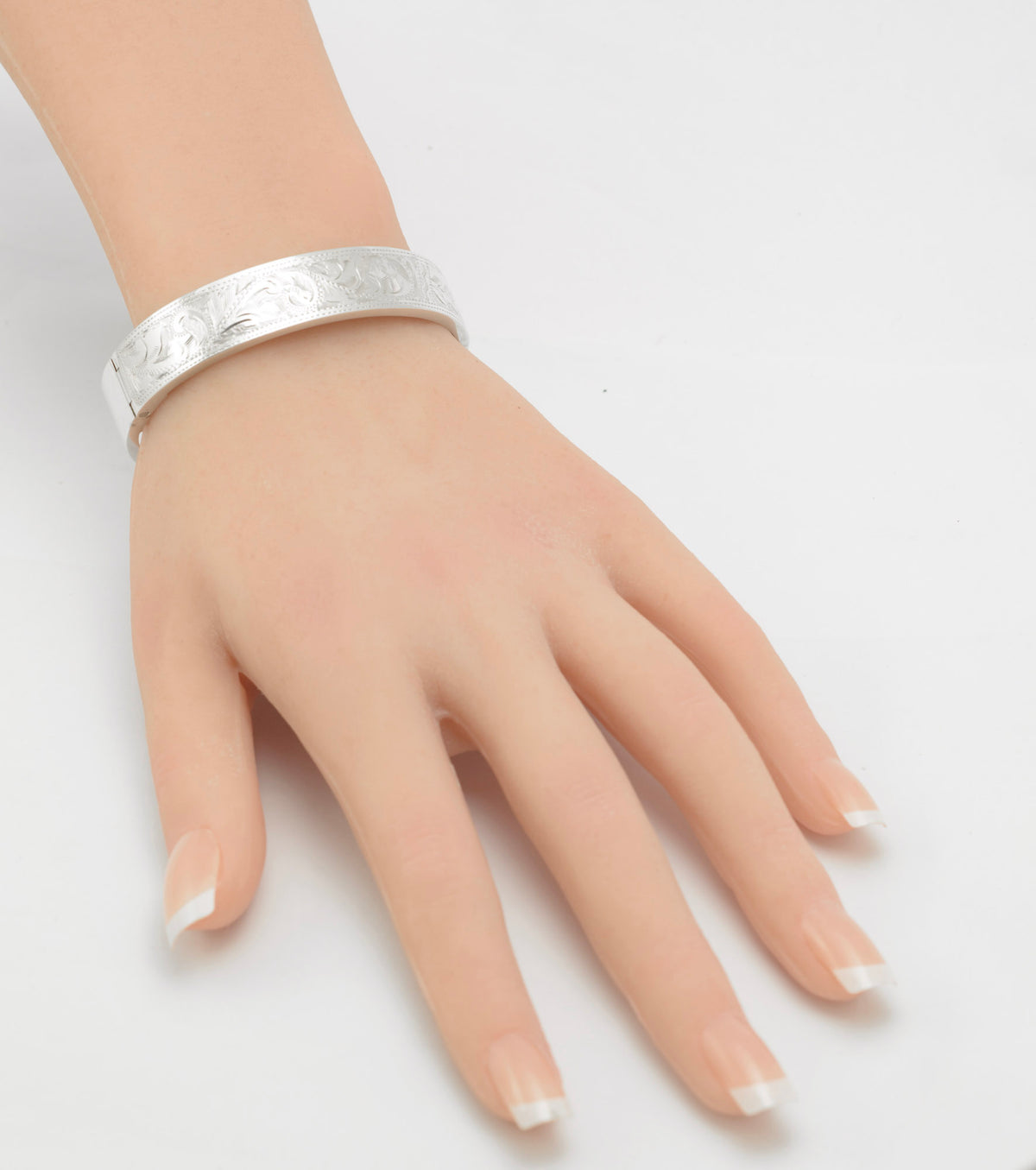 Sterling silver bangle displayed on a hand, showing the floral engraving and broad band