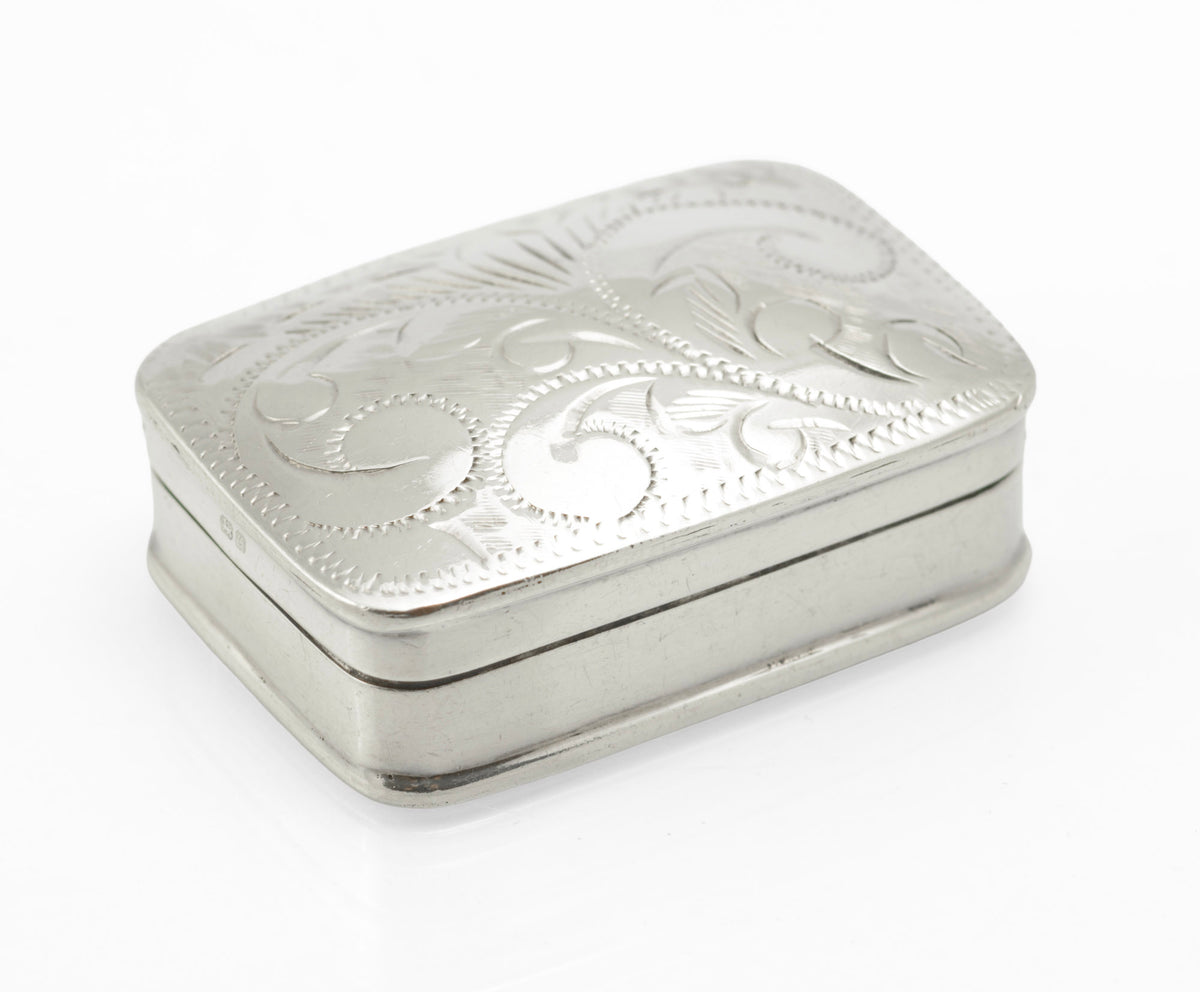 Engraved silver pill box shown with a separate round scale reference item