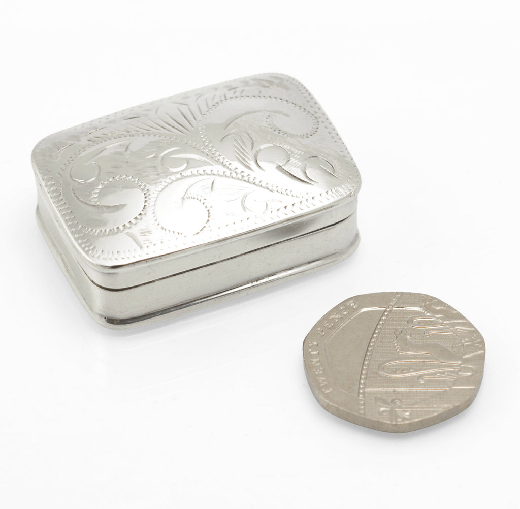 Three quarter view of the silver pill box and engraved lid